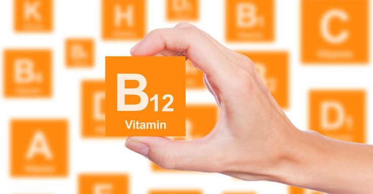 A hand holding an orange block with "B12" and "Vitamin" on it, surrounded by similar blocks.